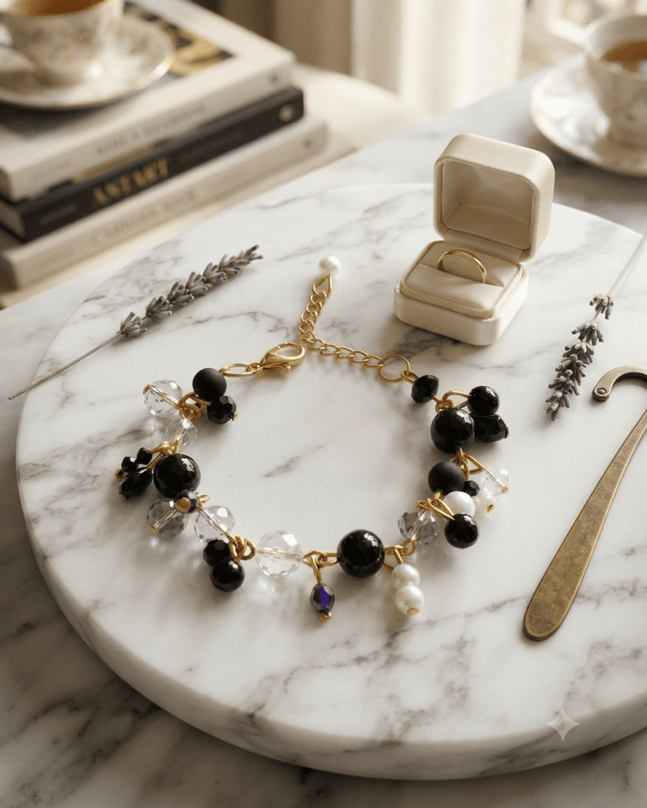 Handmade black and clear crystal bead chain bracelet with gold links resting on a marble surface