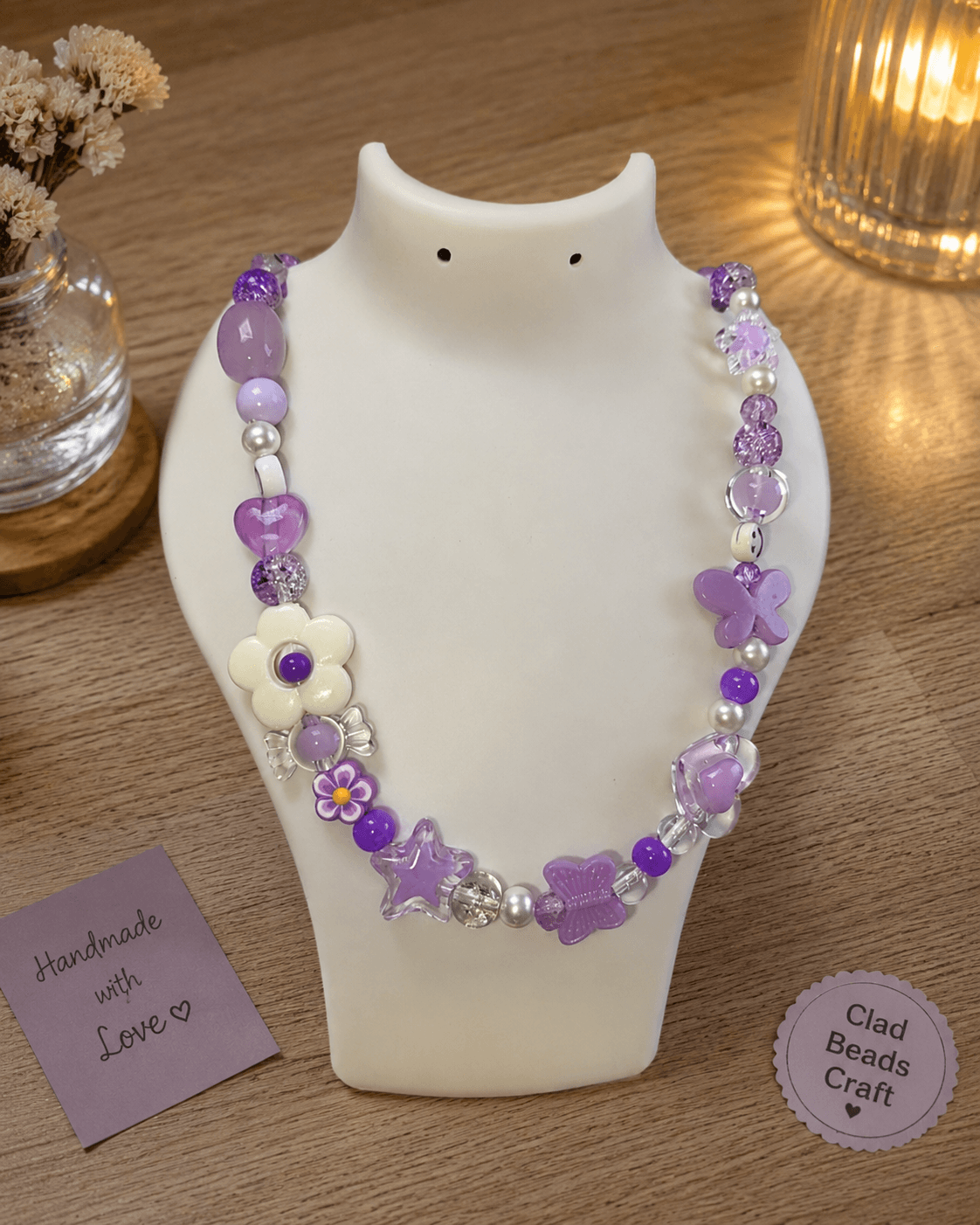Handmade lavender beaded statement necklace with flowers and butterflies displayed on a white bust